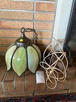 Full view of green slag glass hanging lamp, chain and cord on fireplace hearth