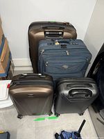 Set of four luggage pieces placed side by side showing size variations and different materials.