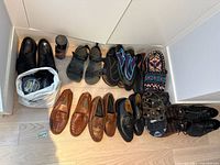 Overview of lot showing 10 pairs of men's shoes including black leather dress shoes, brown woven loafers, black sandals, black hiking/water shoes, colorful winter gaiters, and shoe polish products.