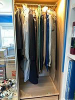 View of men's suit jackets and a cashmere winter jacket hanging in wardrobe