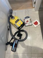 Overview of vacuum canister, hose, wand, nozzle, nozzles, brushes and box of replacement bags