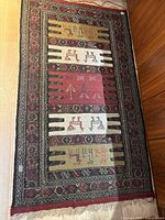 Full view of Persian-style woven rug laid on wooden floor showing complete design and borders.