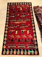 Full view of the red Persian rug laid flat on light wood floor showing entire military design pattern