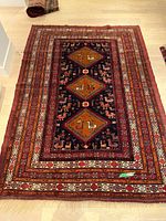 Full view of the unrolled rug on a hardwood floor, showing entire pattern and overall condition