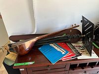 Persian tambour, music stand, music books, and recorder on a table with case visible underneath tambour