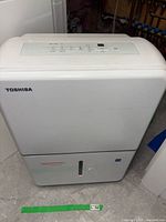 Front view of white Toshiba dehumidifier showing brand and water level indicator.