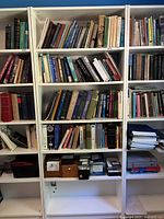 Front view of the white bookshelf fully assembled and filled with books and other items (not included).