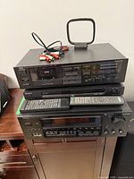 Yamaha stereo tuner/amplifier unit on top of shelf with two remote controls (Sony and Onkyo), RCA audio cables, and antenna on top