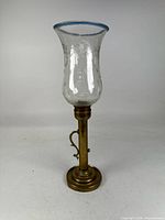 Full view of brass candlestick with glass hurricane shade attached