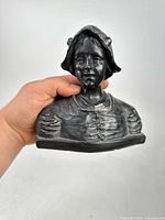 Front view of metal Dutch woman bust showing facial detail and bonnet