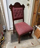 Front view showing carved crest, tufted back, upholstered seat, castered front legs