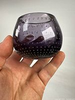 Side view of purple bullicante glass vessel held in hand