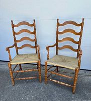Front view of both matching ladder-back armchairs showing overall design and condition