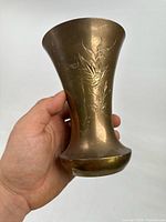 Full view of brass vase held in hand showing overall shape