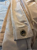 Folded taupe drapes showing grommets and fabric texture