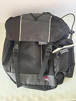 Front view showing flap, buckle straps, mesh pocket, reflective trim