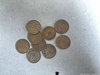 Group of nine bronze Canadian pennies, maple leaf reverse visible, one coin drilled