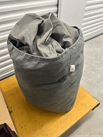 Gray car cover folded inside matching cylindrical storage bag on table