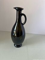 Full view of dark glass jug standing upright