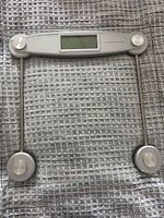Top view of digital glass bathroom scale showing platform, rods, sensors and display