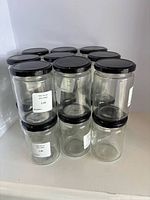 Front view showing stacked clear glass jars with black lids