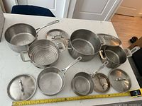 All pots, lids and steamer laid out showing quantity and condition.