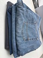 Stack of folded blue jeans, jean shorts and dark gray pant