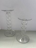 Both clear glass bubble stem candle holders side by side