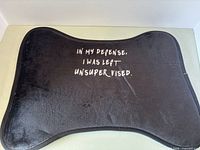 Front of black dog bone-shaped pet mat with humorous phrase