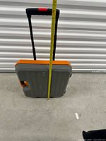 Toolcase standing upright with telescopic handle extended, tape measure showing height