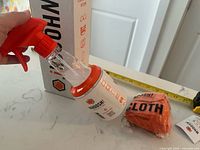 Side view of spray bottle, cloth, and box