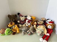 Front view of 13 plush toys lined up showing each animal and outfits