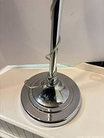 Base of chrome floor lamp showing weighted round base and upright post