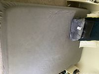 Top view of bed showing full size mattress with grey sheet and pillows