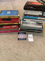 Group shot of two stacks of books with Nixon pin in foreground