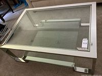 Full view of rectangular chrome and glass coffee table showing glass top, chrome legs, and frosted lower shelf