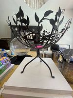 Side view of metal bowl showing leaf motif, tripod base, clear crystal accents