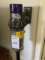 Vacuum mounted on wall showing main body and dust bin