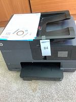 HP OfficeJet Pro 8610 printer with setup disc and paperwork visible on top