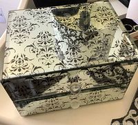 Mirrored jewelry box showing damask pattern and drawers