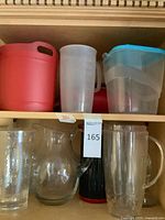 Cabinet showing multiple plastic and glass pitchers on two shelves
