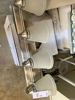 Three-light brushed nickel vanity light with frosted glass shades on backplate