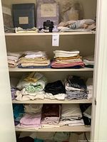 Closet shelves with folded linens, packaged sheet sets and inflator visible