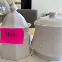 Two white ceramic sugar bowls side by side showing shapes and lids