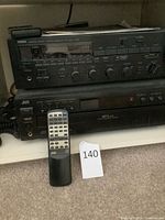 Yamaha receiver stacked above JVC 5-disc CD changer with JVC remote visible