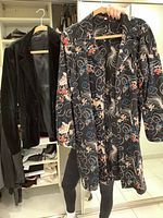 Black velvet blazer hung in closet with patterned long jacket displayed