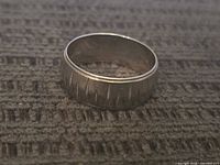Ring upright on textured surface showing geometric notch pattern.