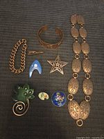 All jewelry pieces displayed on dark textile background for scale and detail.