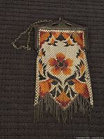 Full view of the antique metal mesh purse showing colorful floral design, metal frame, and chain handle.