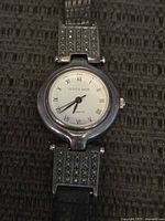 Front view of the Judith Jack watch showing round silver case, white dial with Roman numerals, and marcasite-studded band.